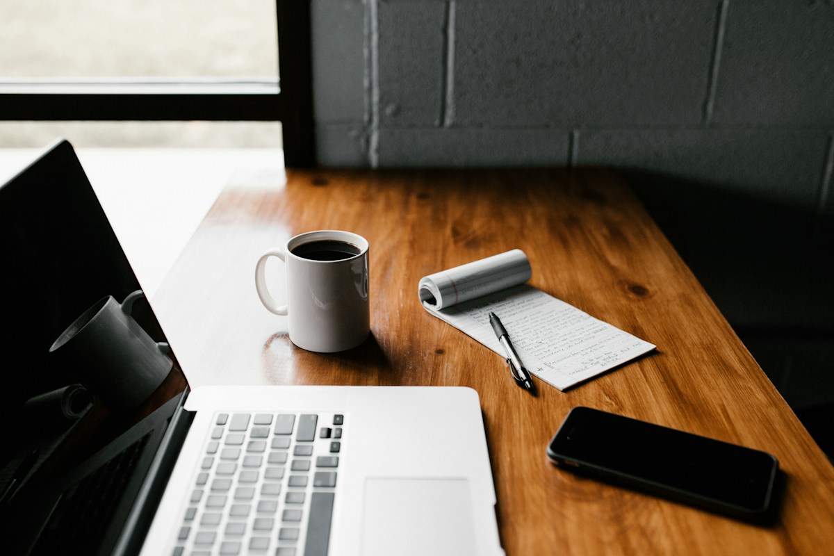 An editorial workspace with a laptop and notebook for researching and crafting content